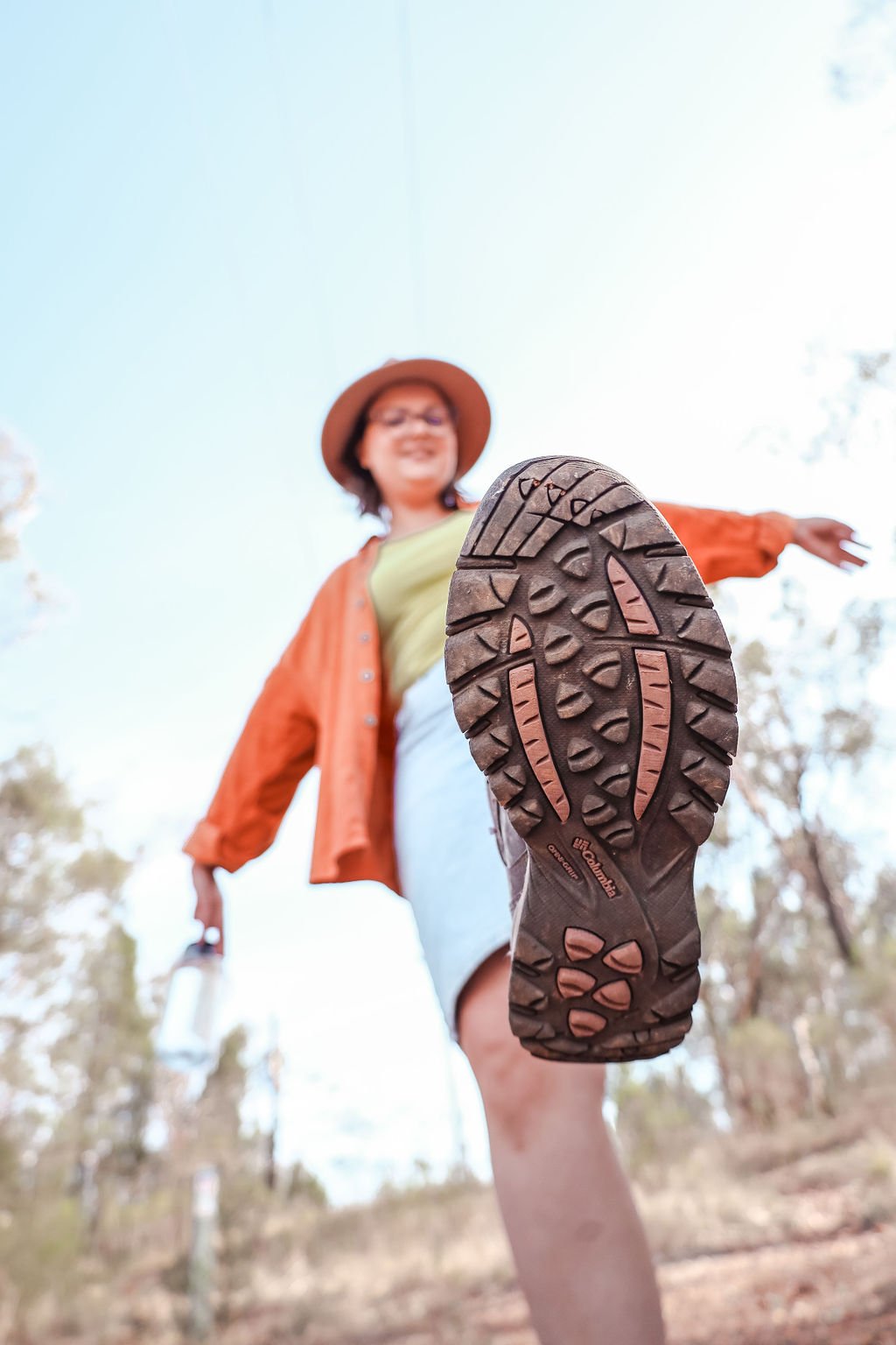 Kreete wearing a hat taking a step photographed from the ground showing the sole of the hiking boot in focus
