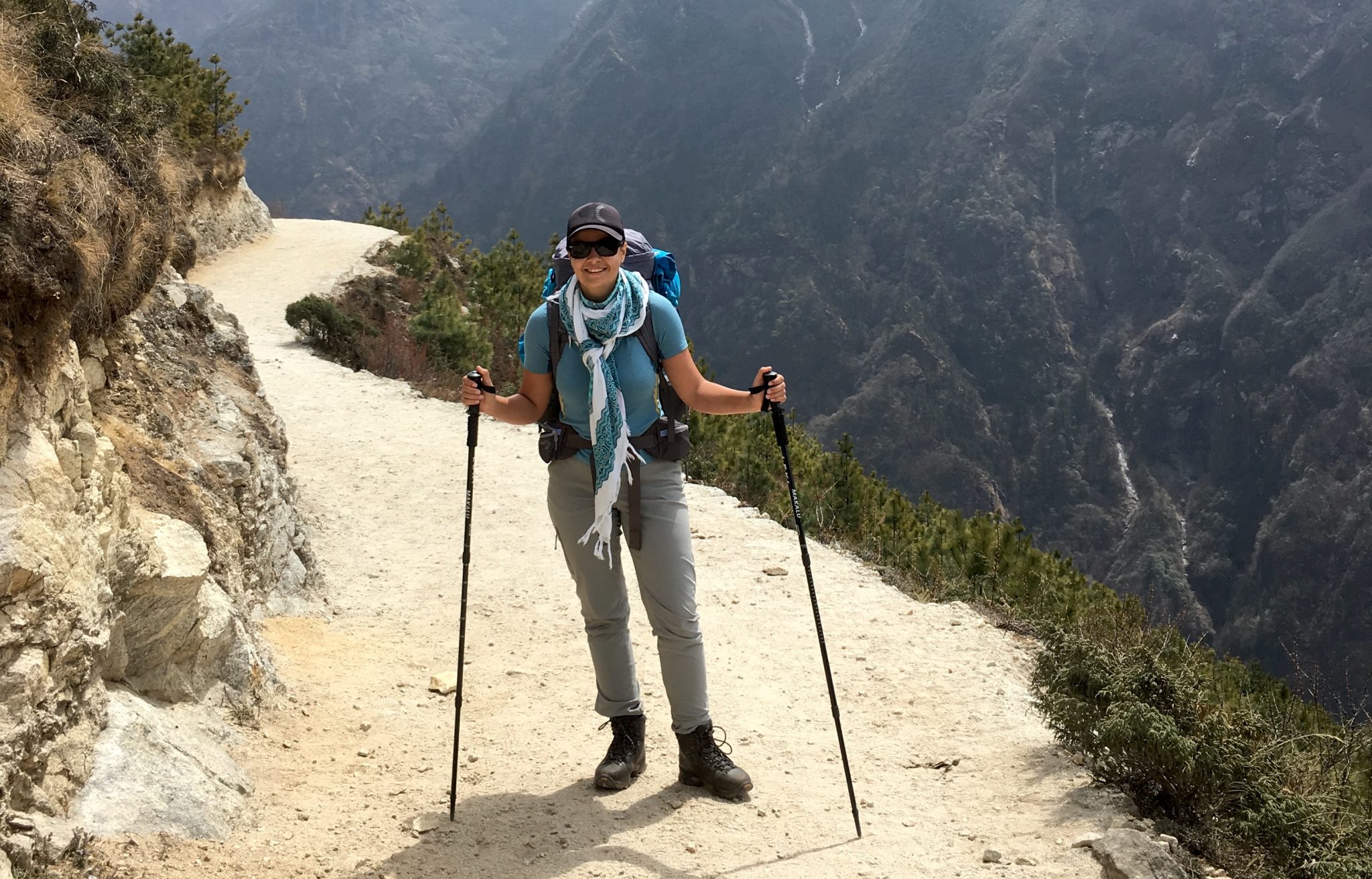 A hiker with trekking poles on a mountain trail.